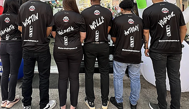 El equipo de Los Panas de espaldas frente al local, con playeras negras que llevan su nombre escrito a mano y un poste de barbero dibujado