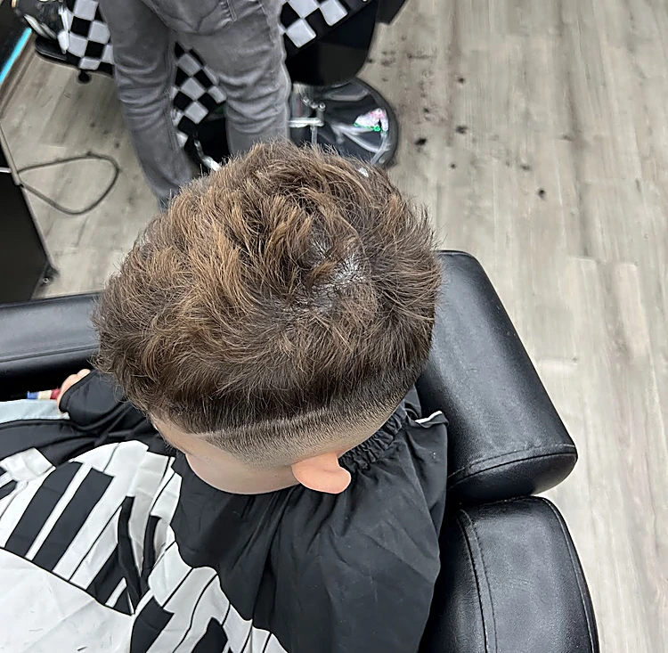 Corte de niño visto desde arriba: degradado bajo en los lados y textura arriba, con capa estampada de teclas de piano